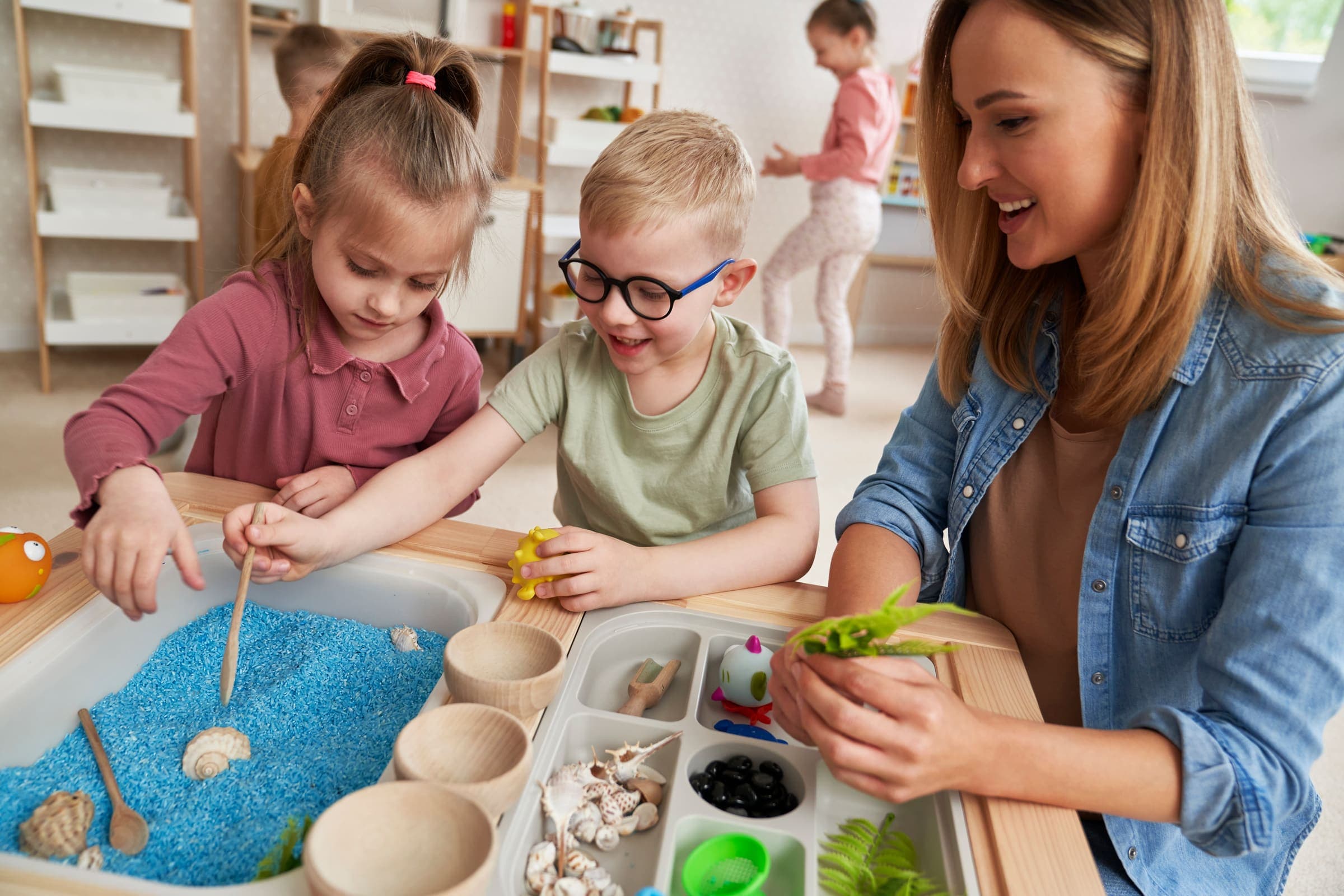 Early childhood educator working with children at a sensory table