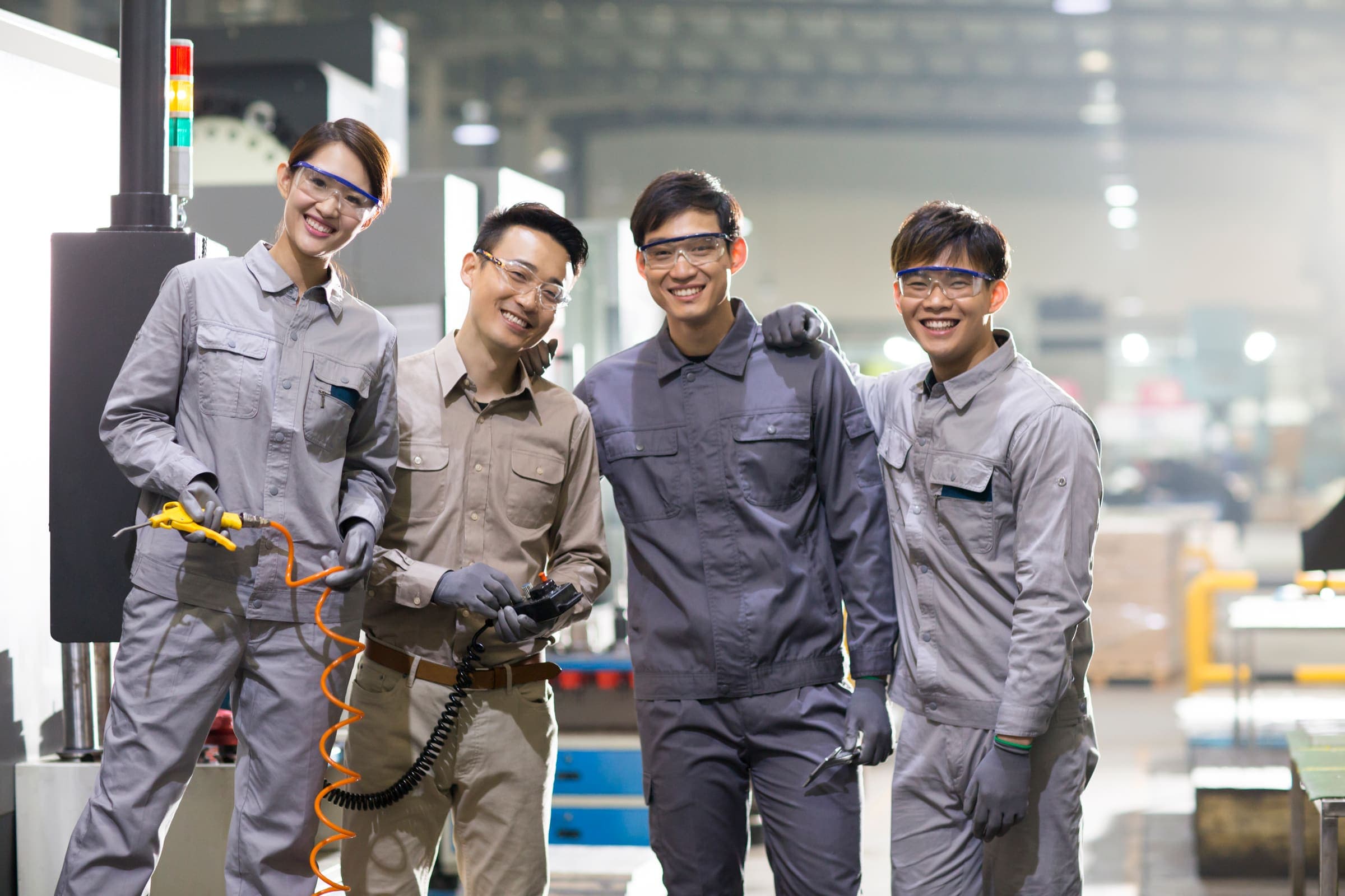 Smiling workers in a manufacturing factory wearing safety equipment